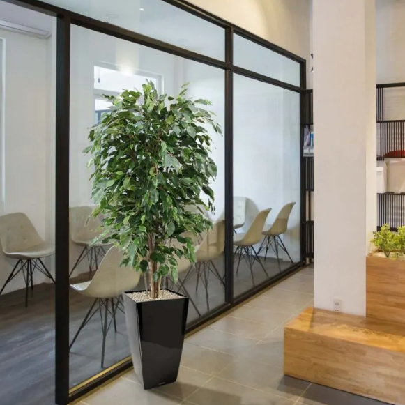 Decoratieve kunstplant met natuurlijke uitstraling in zwarte keramische pot, ideaal voor woonkamer of kantoor.