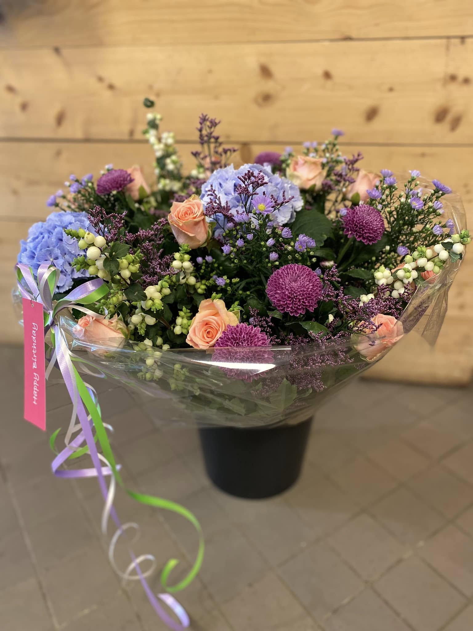 Modern zakelijk bloemstuk in een glazen vaas op een witte kantoorreceptie door Business Plants.