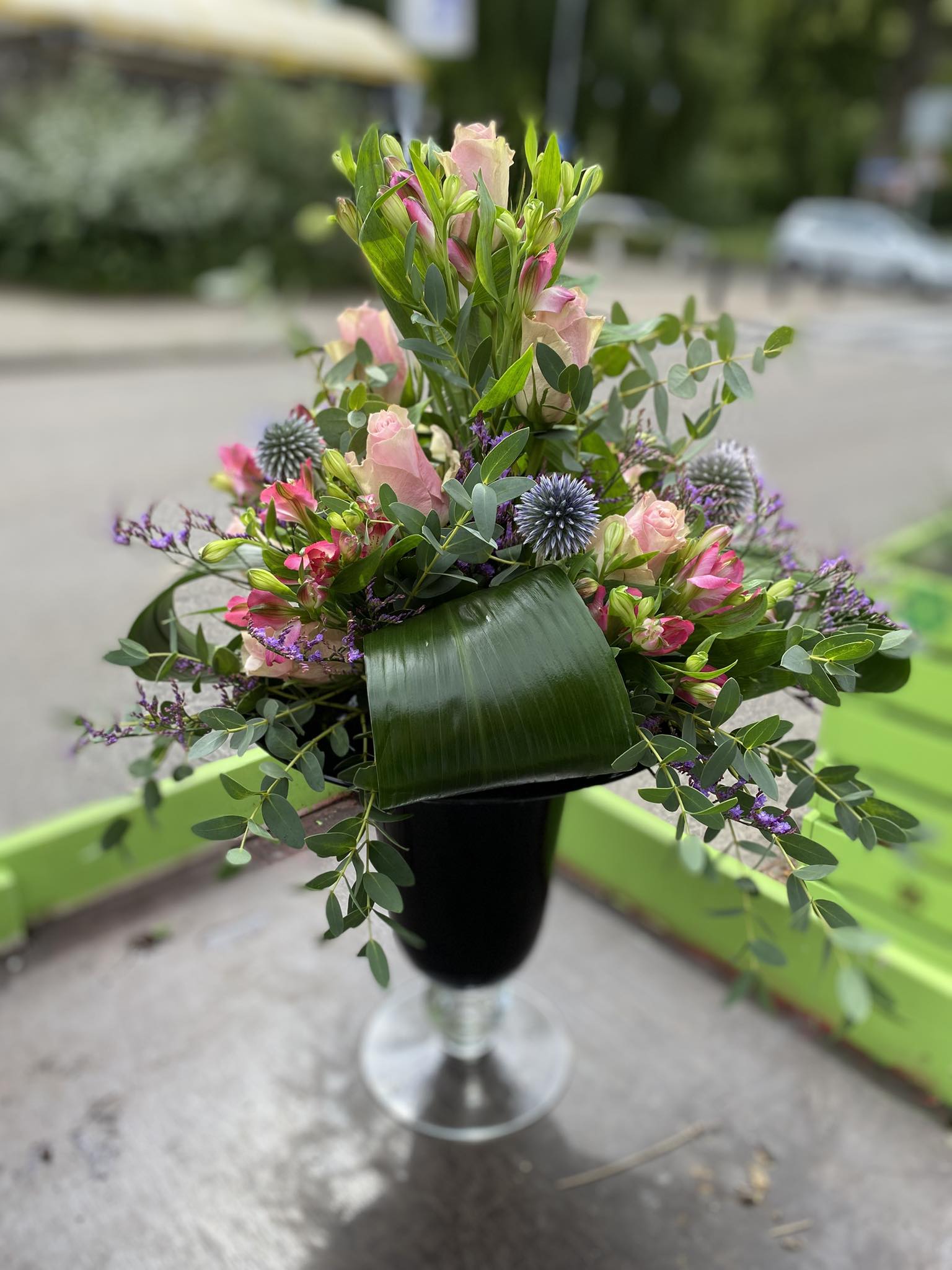 Modern zakelijk bloemstuk in een glazen vaas op een witte kantoorreceptie door Business Plants.