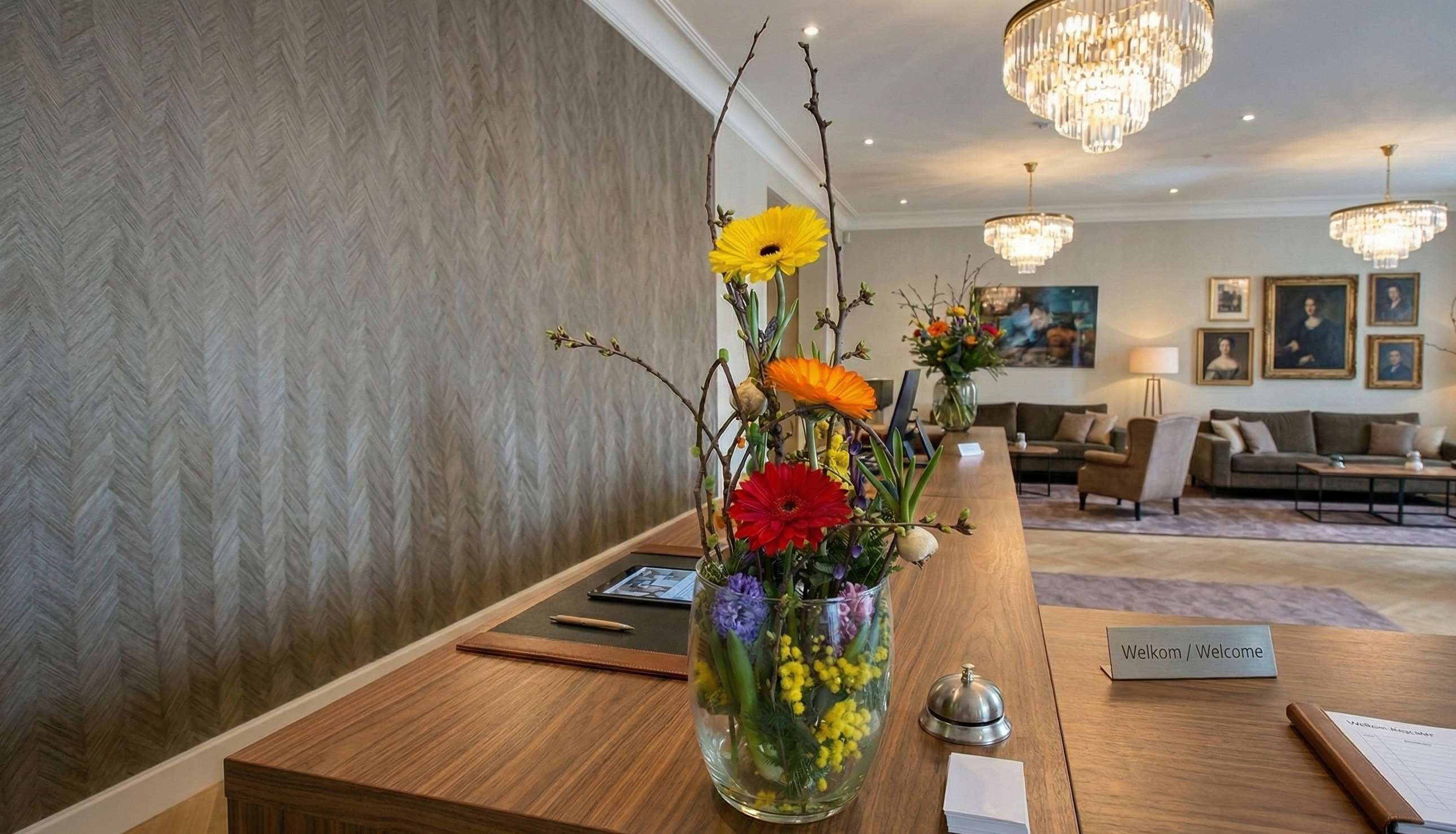 Modern zakelijk bloemstuk in een glazen vaas op een witte kantoorreceptie door Business Plants.